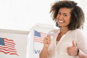 Young woman holding voting badge and smiling
