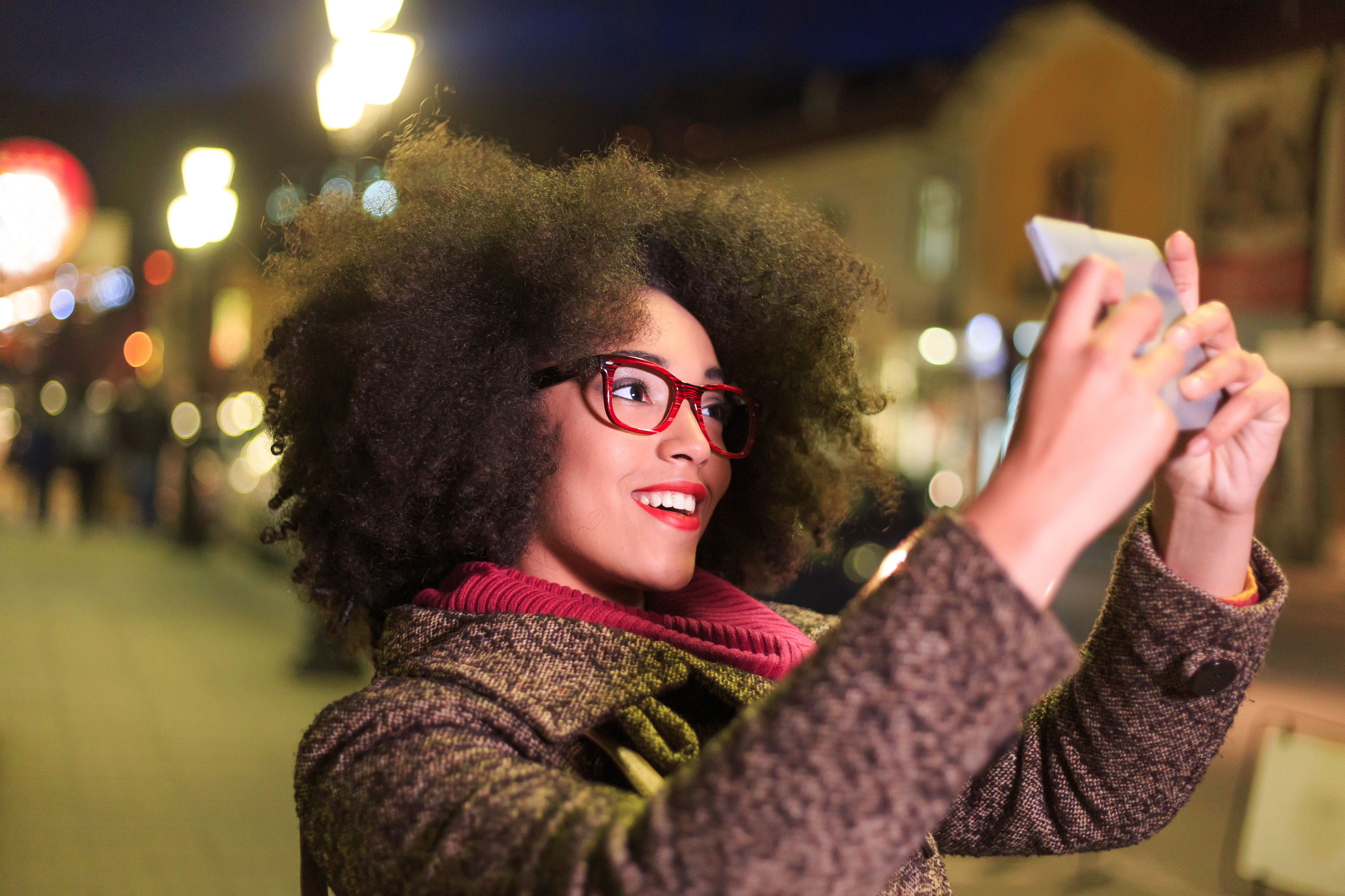 Smiling young african woman making selfie on street at night