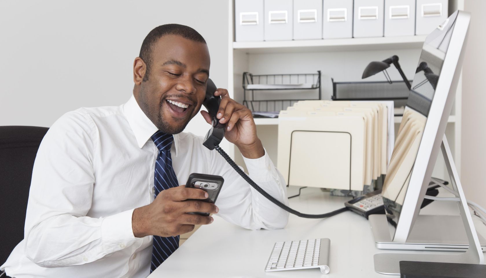 Black businessman using two telephones at one time