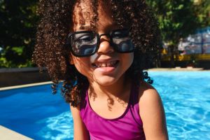 Portrait of a dark-skinned child in a swimsuit near the pool. Portrait of a girl. An active and fun pastime for a child. Swimming is an active sport. Summer. Summer vacation. Vacation.