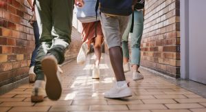 Late and active school children running or walking in a hallway or education setting on the way to class. Low angle feet of a group of young, little students rushing or going to play during break