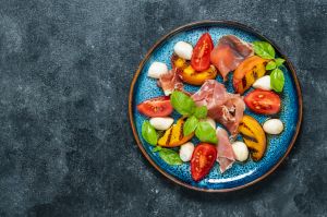 Grilled peach salad with mozzarella, prosciutto ham, red tomato, green basil and soy sauce