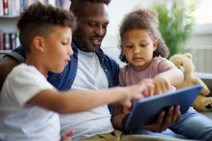 Father and his kids using digital tablet in the living room at home