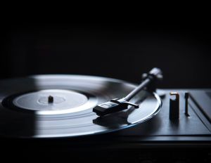 Retro gramophone vinyl player over black background with copyspace.