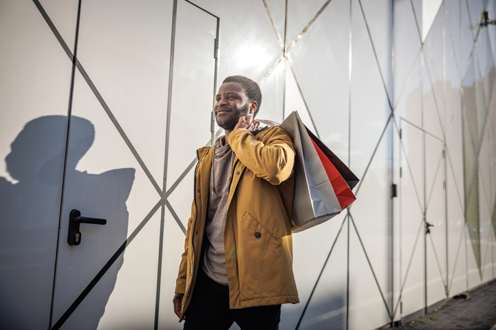 Smiling man carries shopping bags