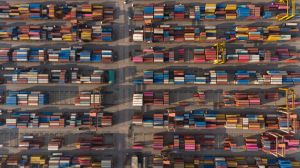 Container ship in export and import business and logistics. Shipping cargo to harbor by crane. Water transport International. Aerial view