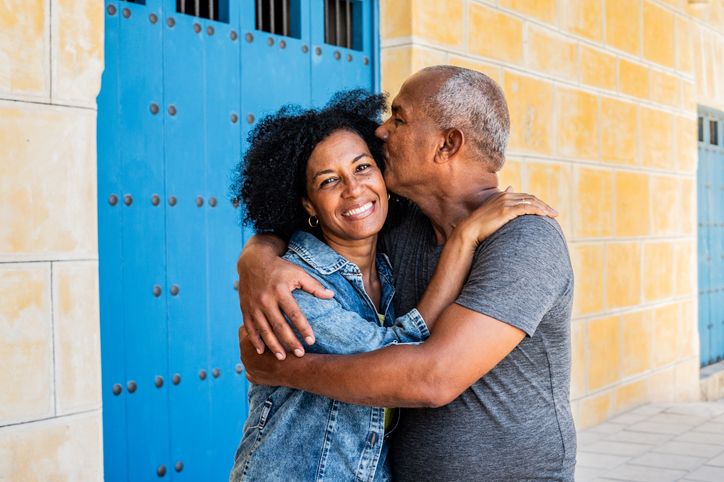 Portrait of mature woman receiving a kiss on the cheek from her husband