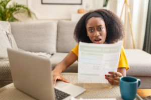 Woman reacting to a bill while working on laptop