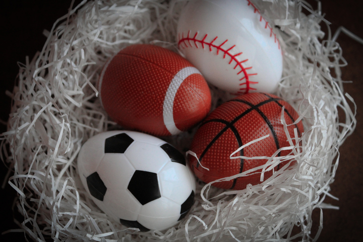 abstract nest with sports themed Easter eggs spring backdrop graphic element eggs soccer football baseball basketball on white grass isolated on dark background