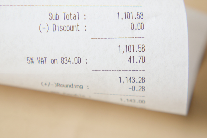 A receipt, coins, and a pencil on a table symbolize finance, transactions, and commerce